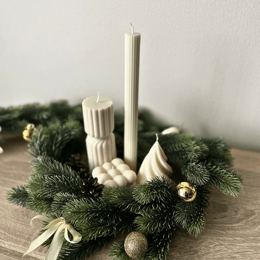 La Bouqe decorative holiday candle set with green pine wreath and gold ornaments on wooden table