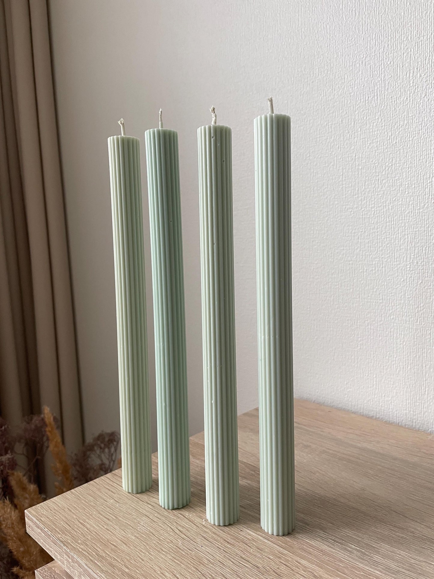 La Bouqe elegant dinner candles 4 pack in soft green with vertical ridges on wood surface