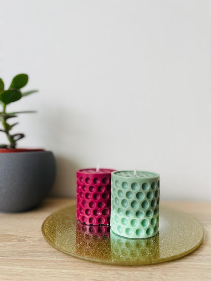 La Bouqe dotted cylindrical handmade candle in green and red colors displayed on a golden tray