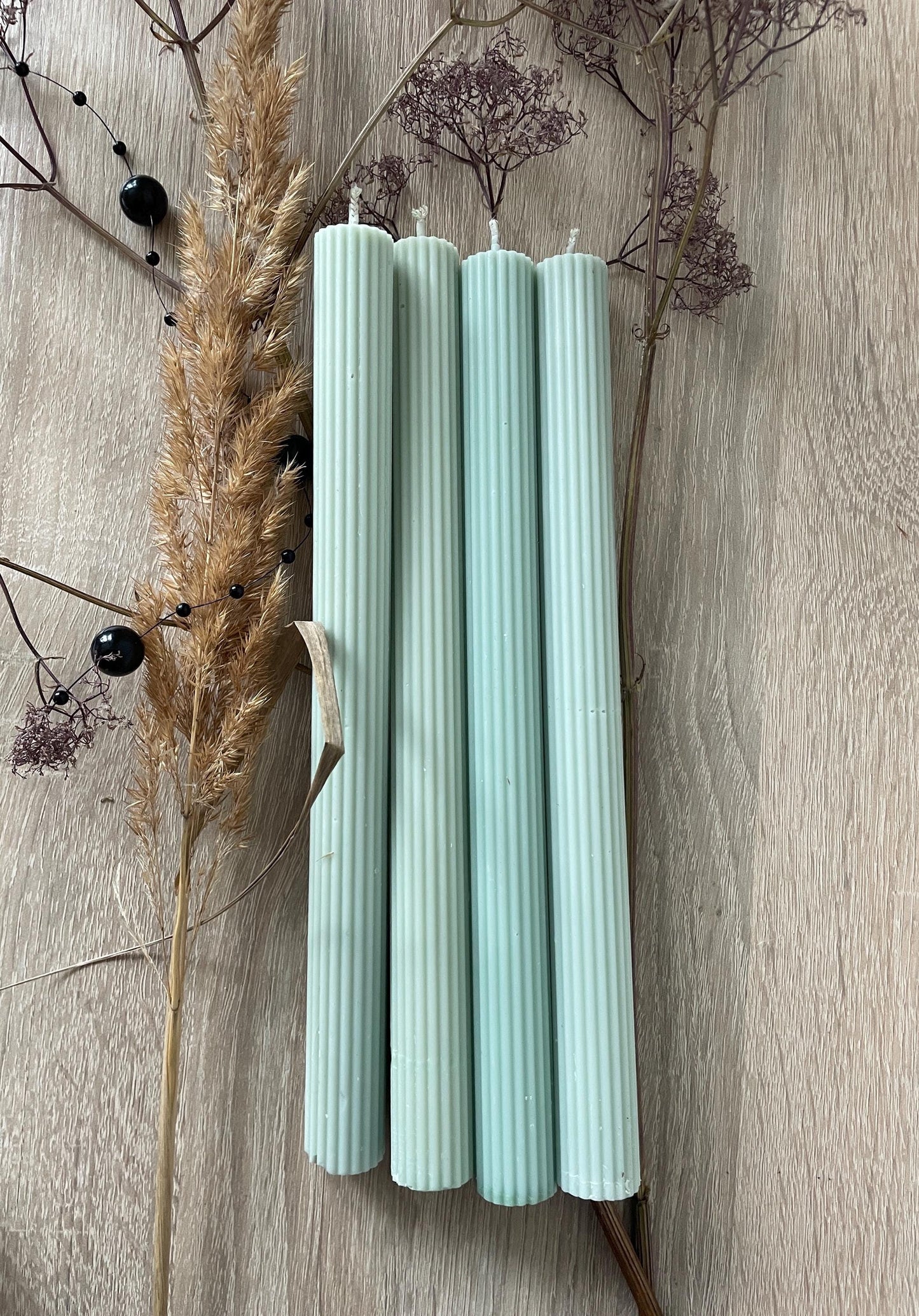 La Bouqe elegant dinner candles 4 pack in soft pastel green with ribbed texture on wooden surface with dried flowers