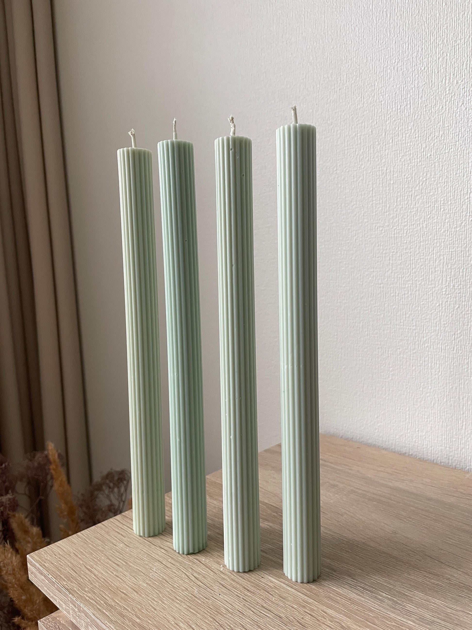 La Bouqe elegant dinner candles 4 pack in soft green with vertical ridges on wood surface