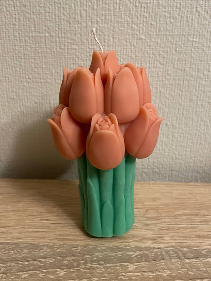 La Bouqe tulip bouquet candle with orange tulip-shaped wax flowers and green stems on wooden table