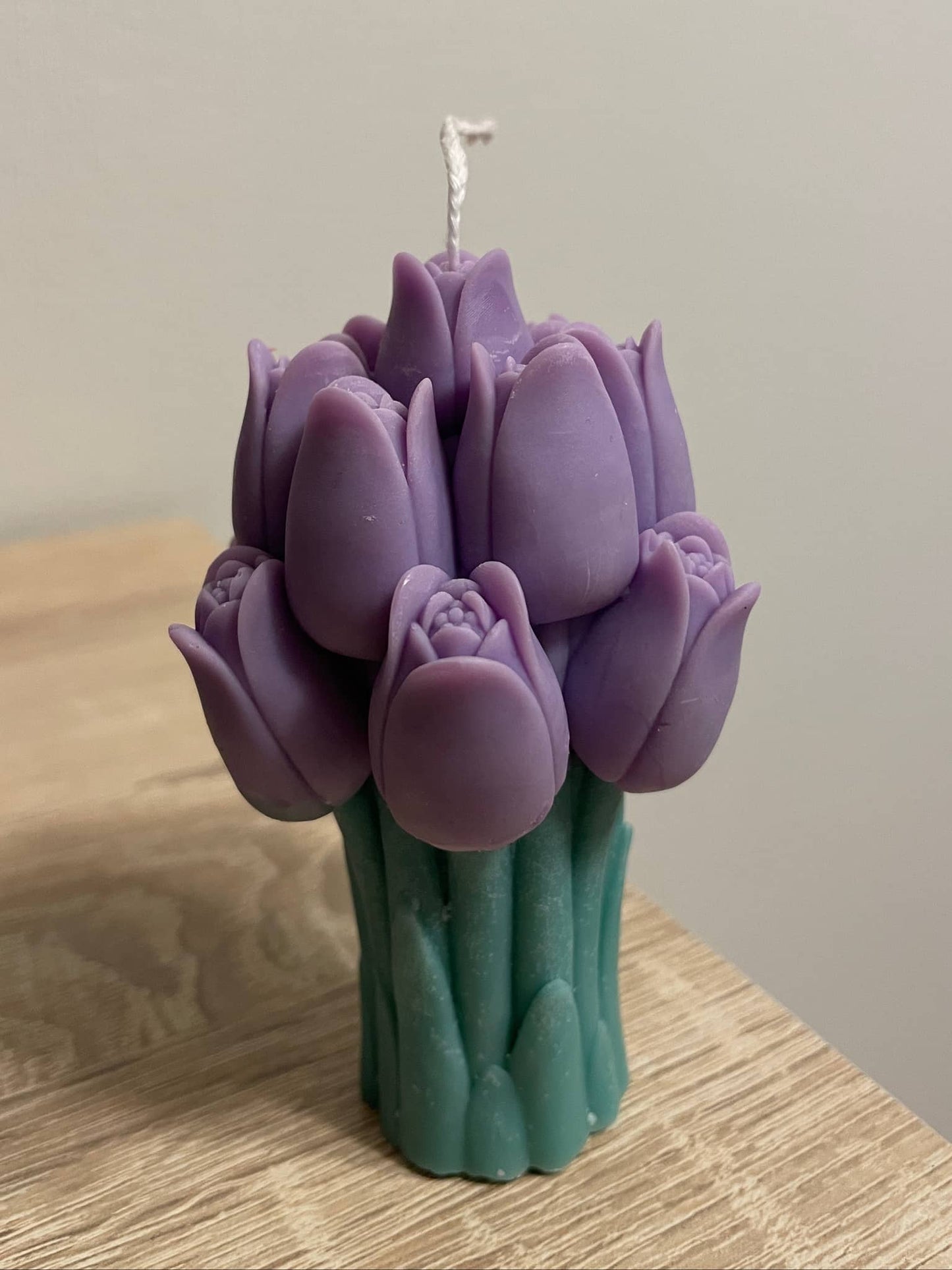 La Bouqe purple tulip bouquet candle with green stem base on wooden surface