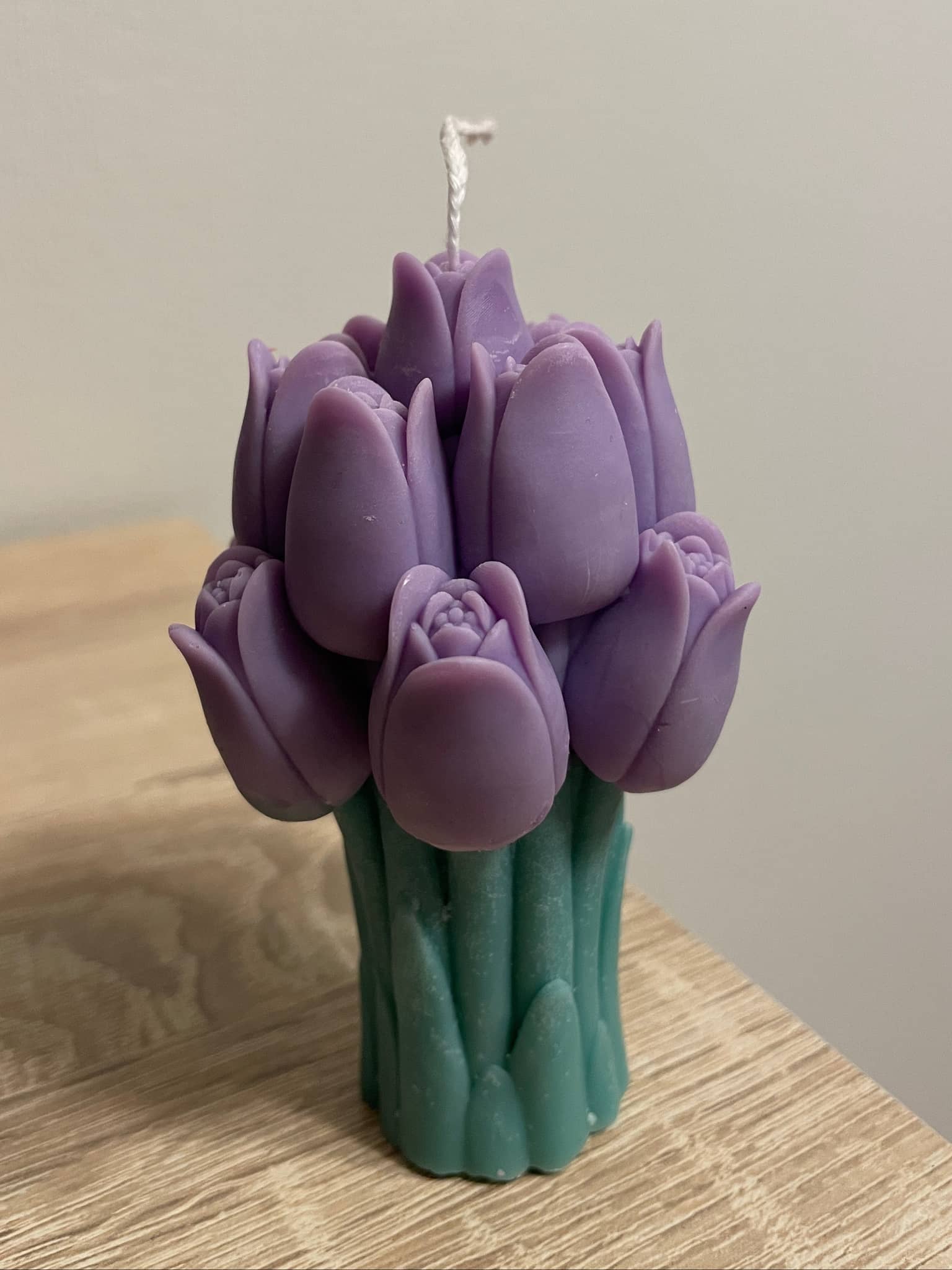 La Bouqe purple tulip bouquet candle with green stem base on wooden surface
