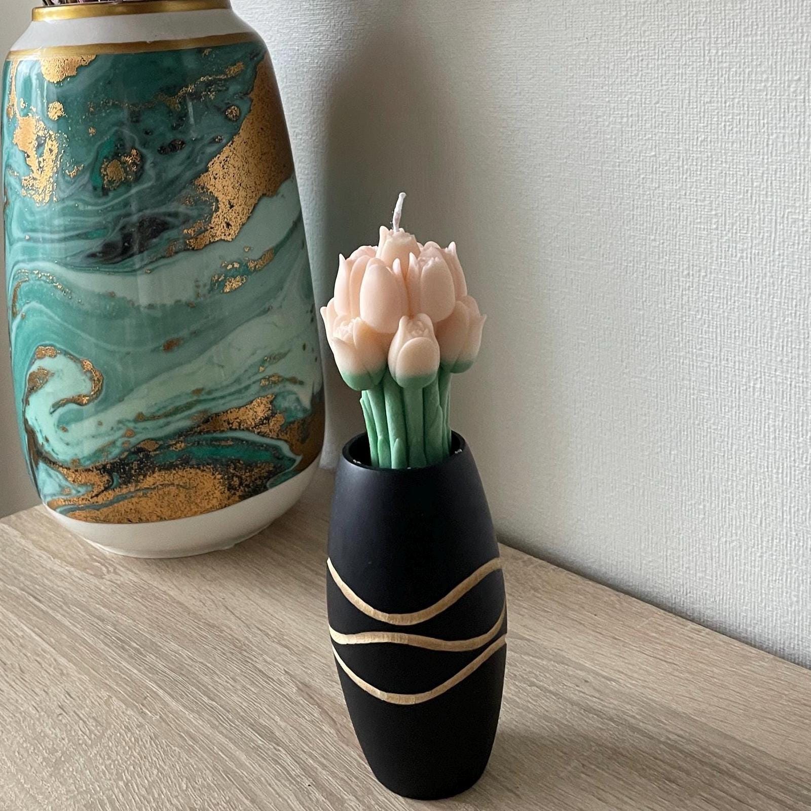 La Bouqe tulip bouquet candle with pink tulip-shaped wax in a black decorative vase on wooden table