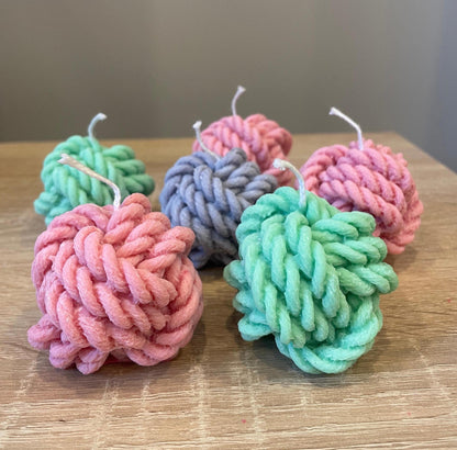 La Bouqe yarn ball soy candles in pastel pink green and blue colors arranged on wooden surface